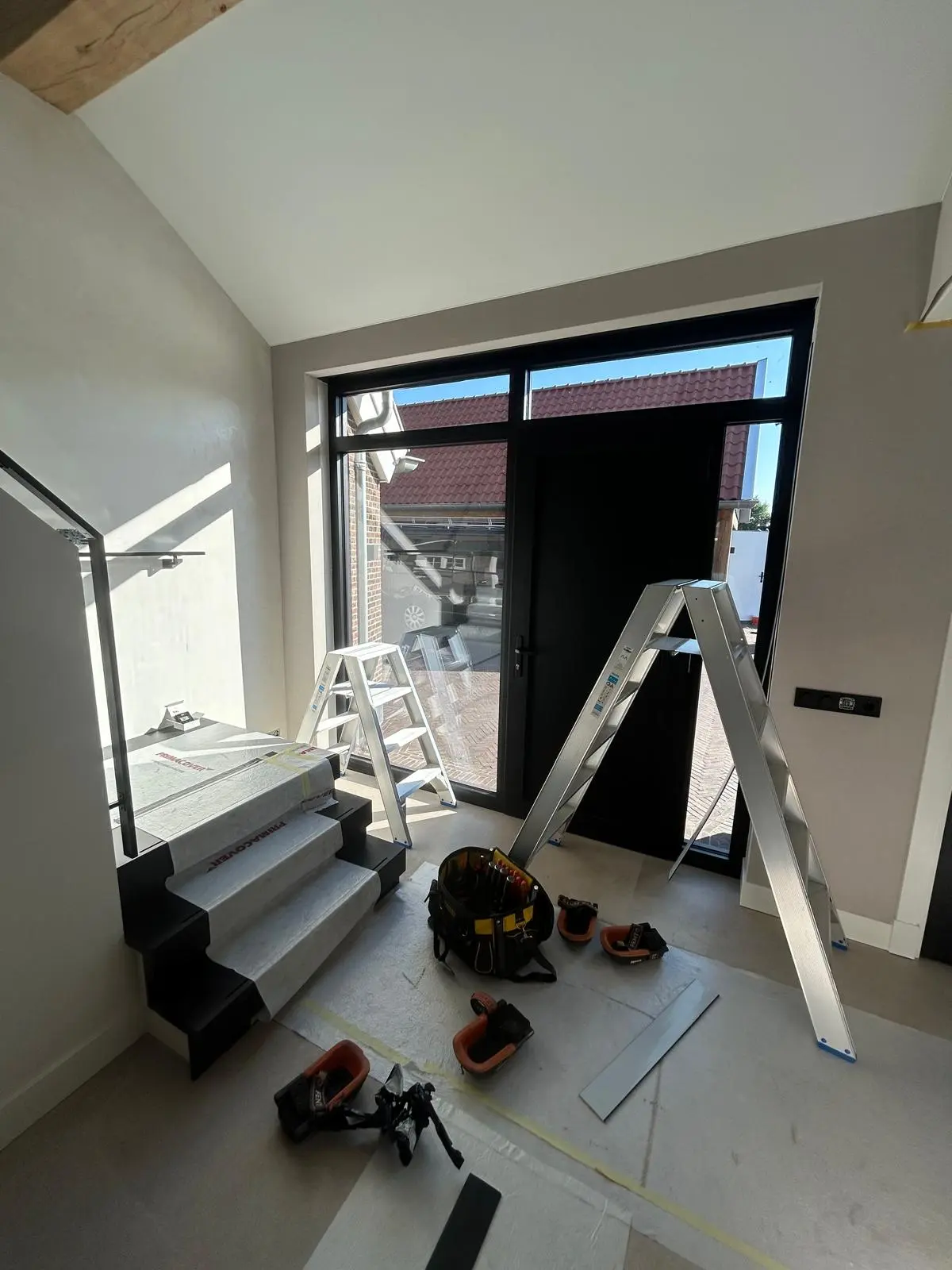 Nieuwbouw hal met glazen voordeur en trap